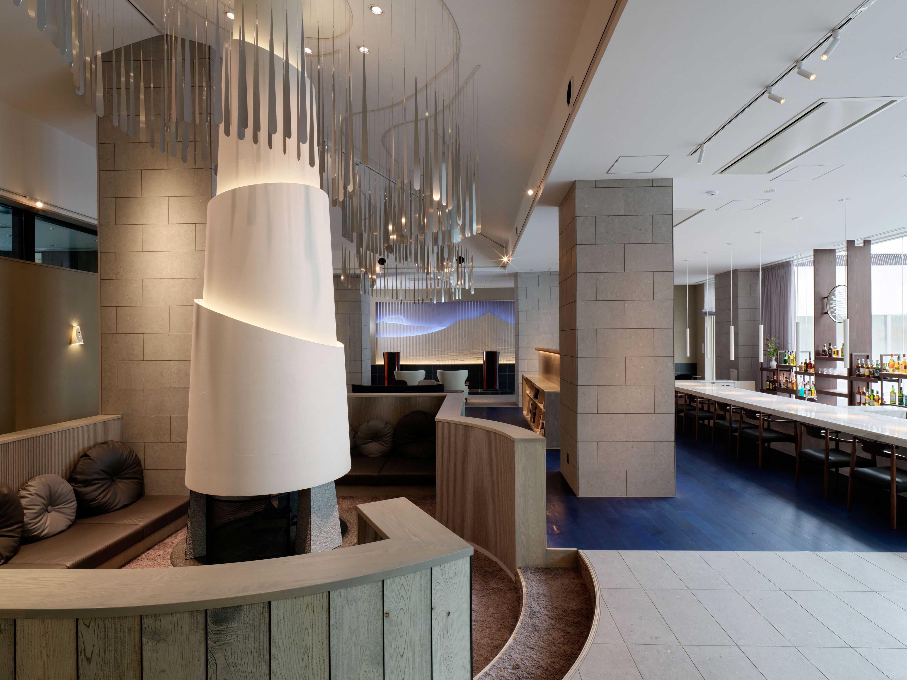 A modern interior with a central seating area, a bar, and a dining space.