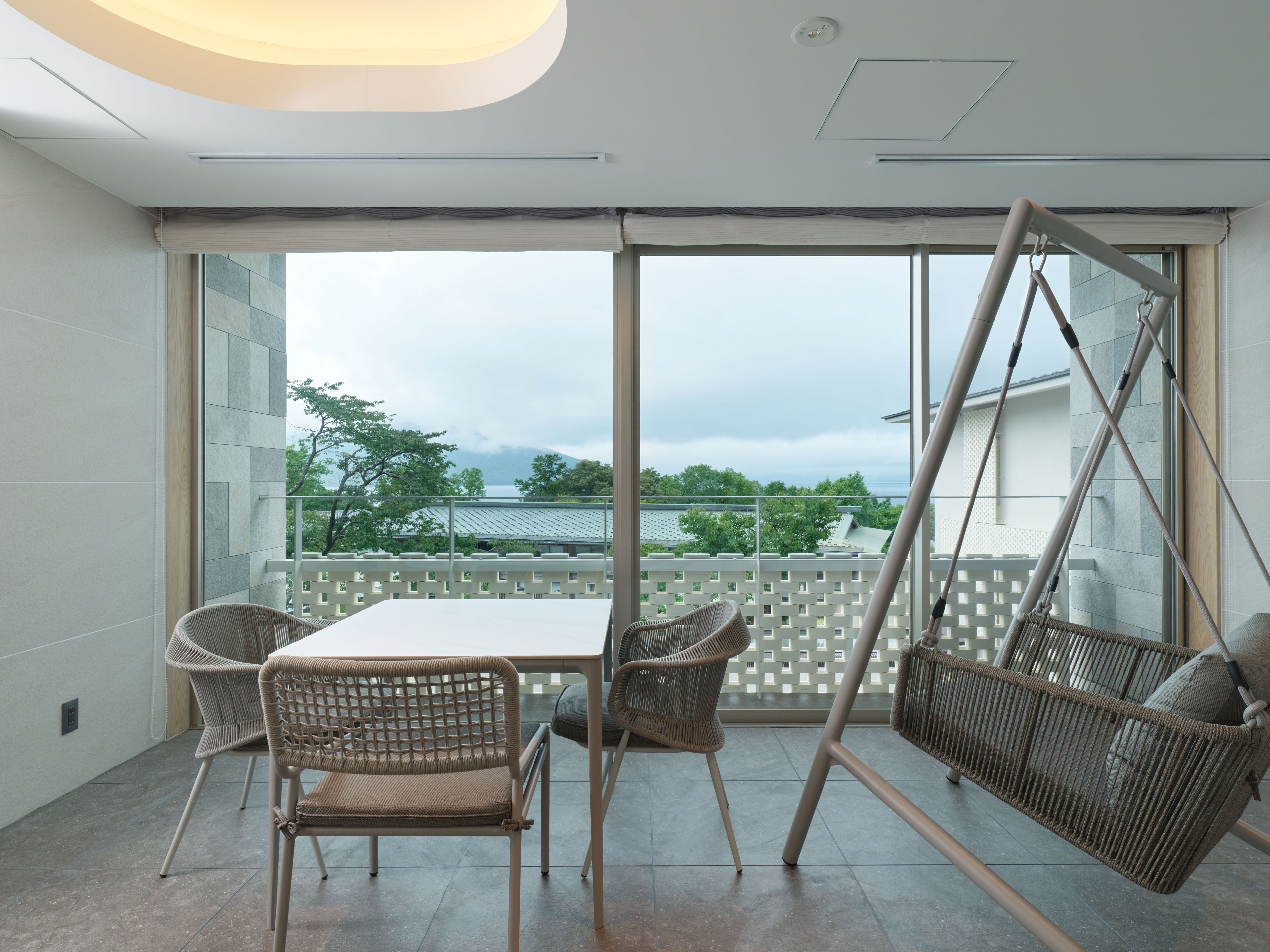 Un balcon avec un fauteuil suspendu, une table et des chaises.