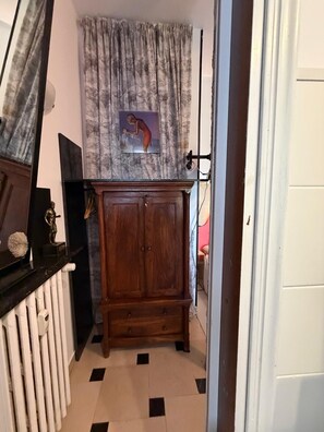 A room with a wooden cabinet, a radiator, and a curtain. - Giò Gio's Little Home—Rho-Sacco-Galeazzi (Milano)