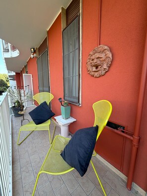 A balcony with yellow chairs, a potted plant, and a decorative wall piece. - Giò Gio's Little Home—Rho-Sacco-Galeazzi (Milano)