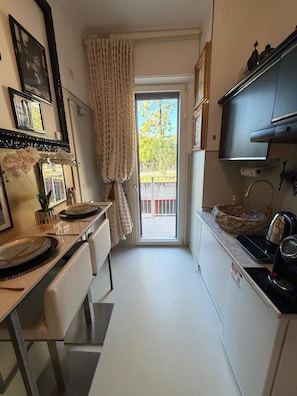 A narrow kitchen with a dining area, a large mirror, and a view to the outside. - Giò Gio's Little Home—Rho-Sacco-Galeazzi (Milano)