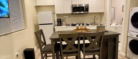 A compact kitchen with a central island, white cabinets, a microwave, and a washing machine.