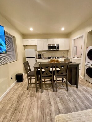 A compact kitchen with a central island, white cabinets, a microwave, and a washing machine. - Brand New Private ADU (Los Angeles)