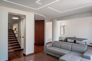 Un salon moderne avec un canapé, une table de ping-pong et un escalier menant à une autre pièce.