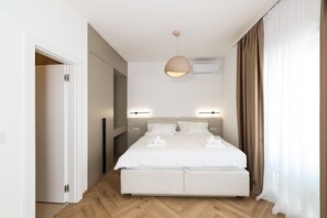 Et moderne hotelværelse med en stor seng, sengeborde med lamper, en aircondition og trægulv.