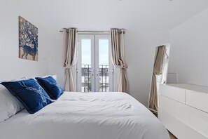 Ein Schlafzimmer mit einem Bett, Vorhängen, einer weißen Kommode und einem Bild an der Wand.