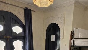 A room with a glass-top table, a patterned rug, a bunk bed, and a door with decorative glass panels.