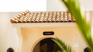 A building entrance with a tiled roof, an arched doorway, and a sign that reads 'Casa de Campo.'