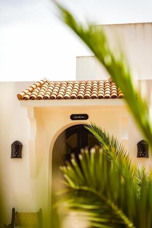 A building entrance with a tiled roof, an arched doorway, and a sign that reads 'Casa de Campo.'