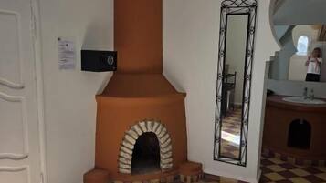 Una habitación con piso de cuadros, chimenea, espejo y puerta.