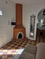 Una habitación con piso de cuadros, chimenea, espejo y puerta.
