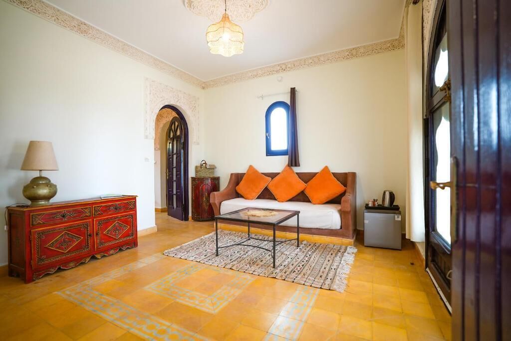 Una sala de estar con un sofá, una mesa de centro, una lámpara, un aparador y una puerta.