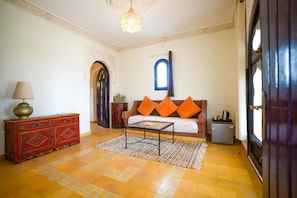 Una sala de estar con un sofá, una mesa de centro, una lámpara, un aparador y una puerta.