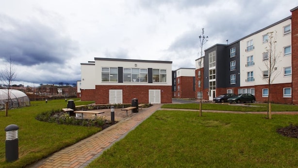 A modern building with a brick facade, a paved walkway, and a grassy area with benches. - Student Only Selly Oak (Birmingham)