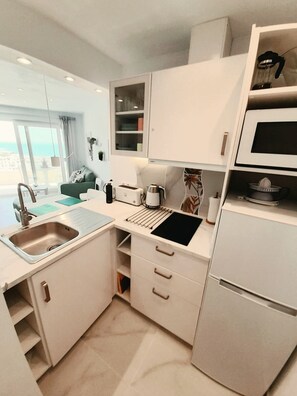 A modern kitchen with a built-in oven, a sink, and a microwave. - Modern studio apartment right on the beach promenade (Torrox-Costa)