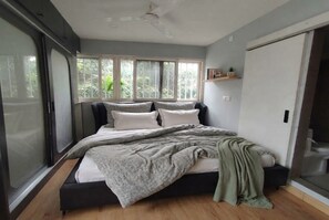 A bedroom with a bed, a window, a ceiling fan, and a door. - Dwell - A place to live (Bengaluru)