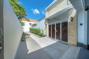 A modern building with a stone facade, a gated entrance, and a paved walkway. - Addikha Villa by Betterplace (Canggu)
