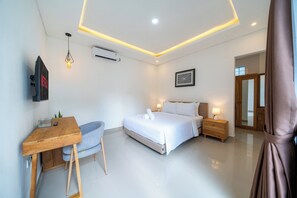 Habitació d'hotel moderna amb llit, taula de nit i escriptori amb cadira.