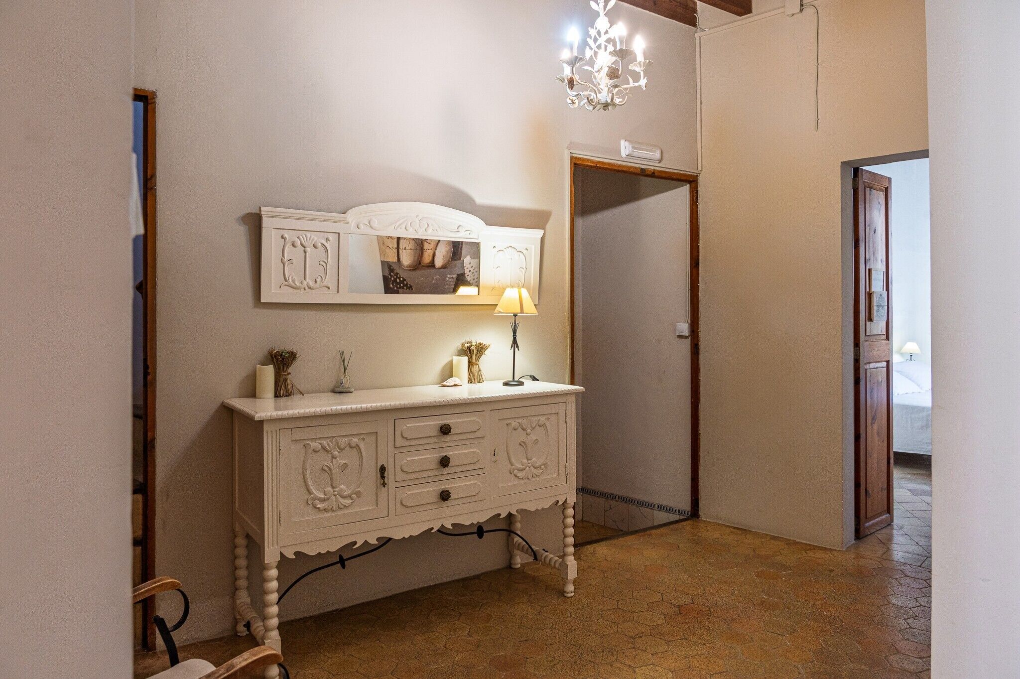 A white dresser with drawers and a mirror, a lamp, and decorative items on top.