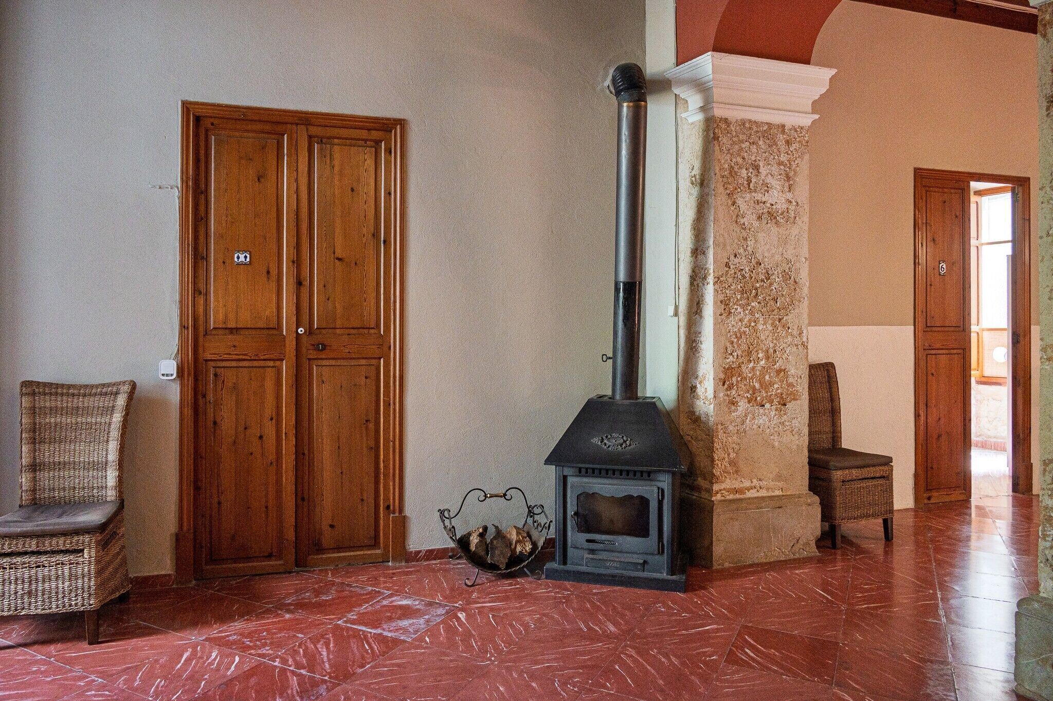 A room with a fireplace, wooden doors, and wicker furniture.