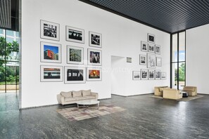 Eine geräumige Galerie mit modernem Interieur, inklusive einer Couch und einem Couchtisch, sowie Wänden mit gerahmten Fotografien.