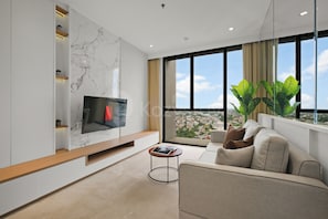 A modern living room with a flat-screen TV, a sofa, a coffee table, and a large window with a city view. - Brunn by Kozystay - Cilandak (South Jakarta)