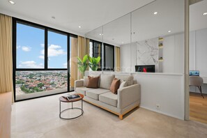 Ein modernes Wohnzimmer mit einer Couch, einem Couchtisch und einem großen Fenster mit Blick auf die Stadt.