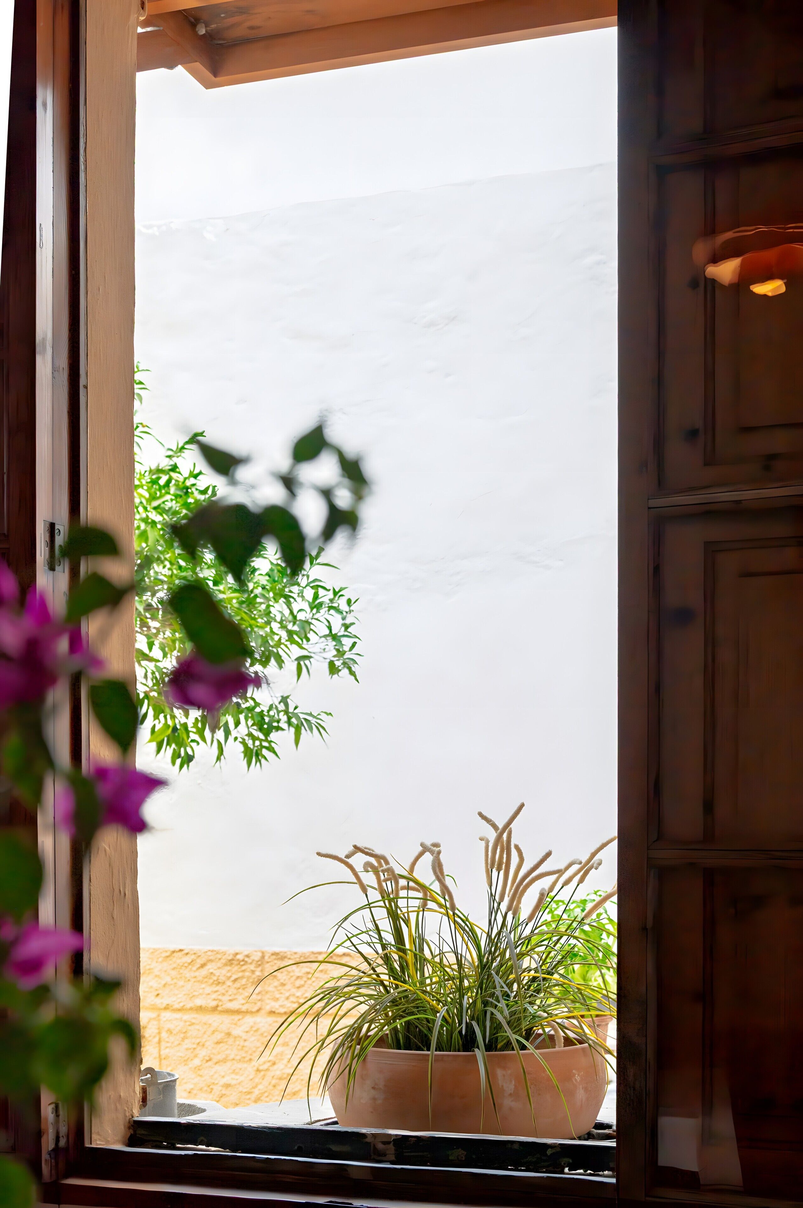 A wooden interior with a window overlooking a sandy beach.