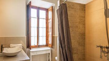 Een badkamer met een wastafel, een raam en een douche.