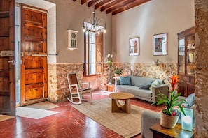 Ein rustikales Wohnzimmer mit Holztür, Steinwand, Schaukelstuhl, Sofa und einer Chandelier.