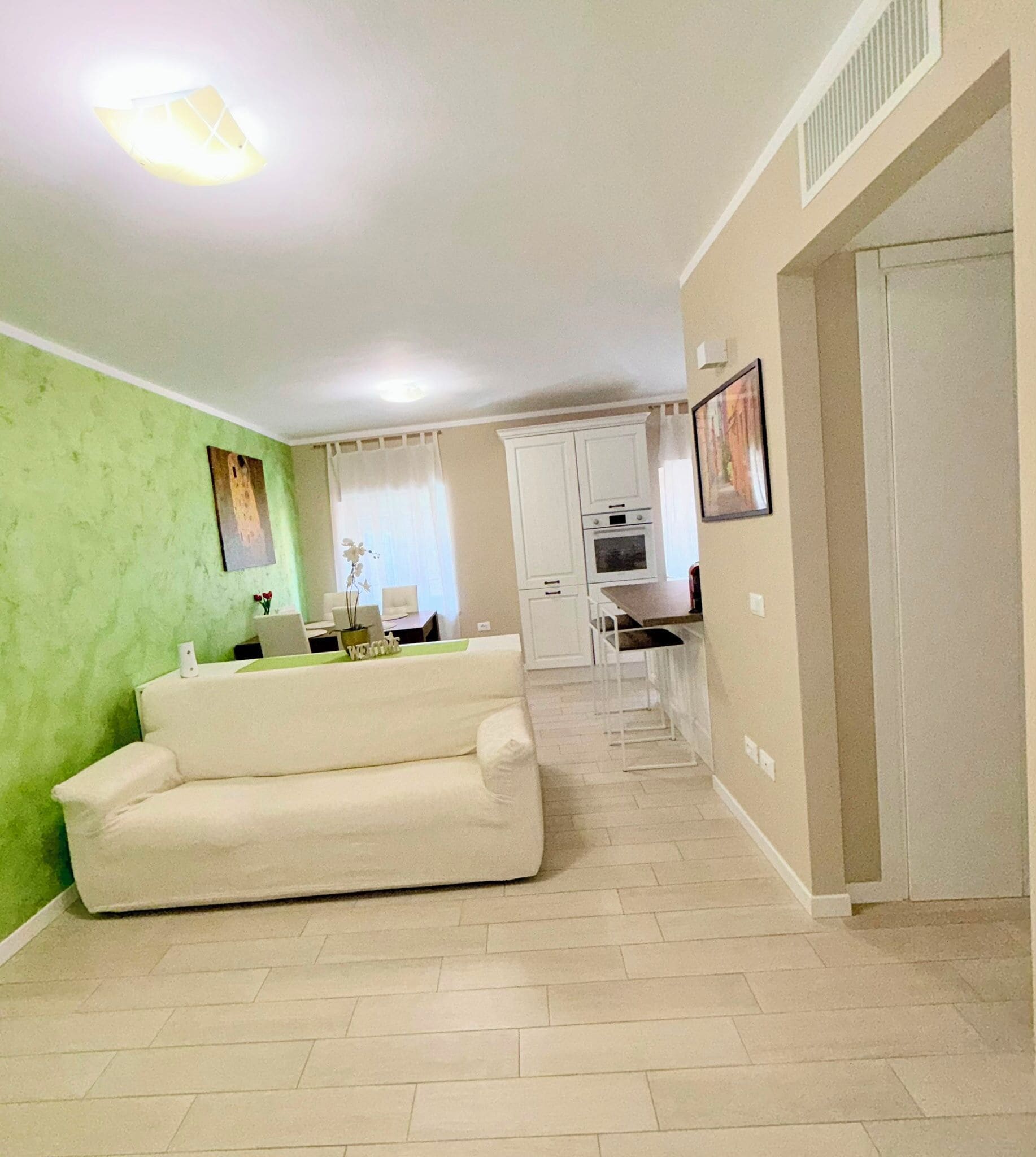 A living room with a sofa, a dining area with a table and chairs, and a kitchen with cabinets and appliances.