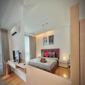 A modern hotel room with a bed, bedside table, and a large mirror. - Cozy Private Home - Steps to BTS & MRT Sukhumvit (Krung Thep Maha Nakhon)