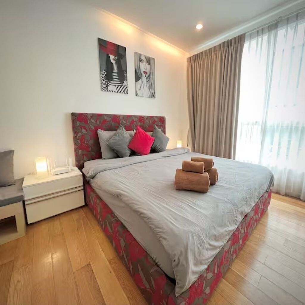 Un dormitorio moderno con una cama grande, una mesita de noche y un televisor montado en la pared.