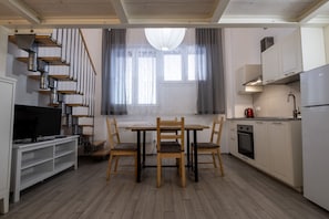 Eine moderne Küche mit Esstisch, Stühlen, einem Fernseher und einer Treppe.