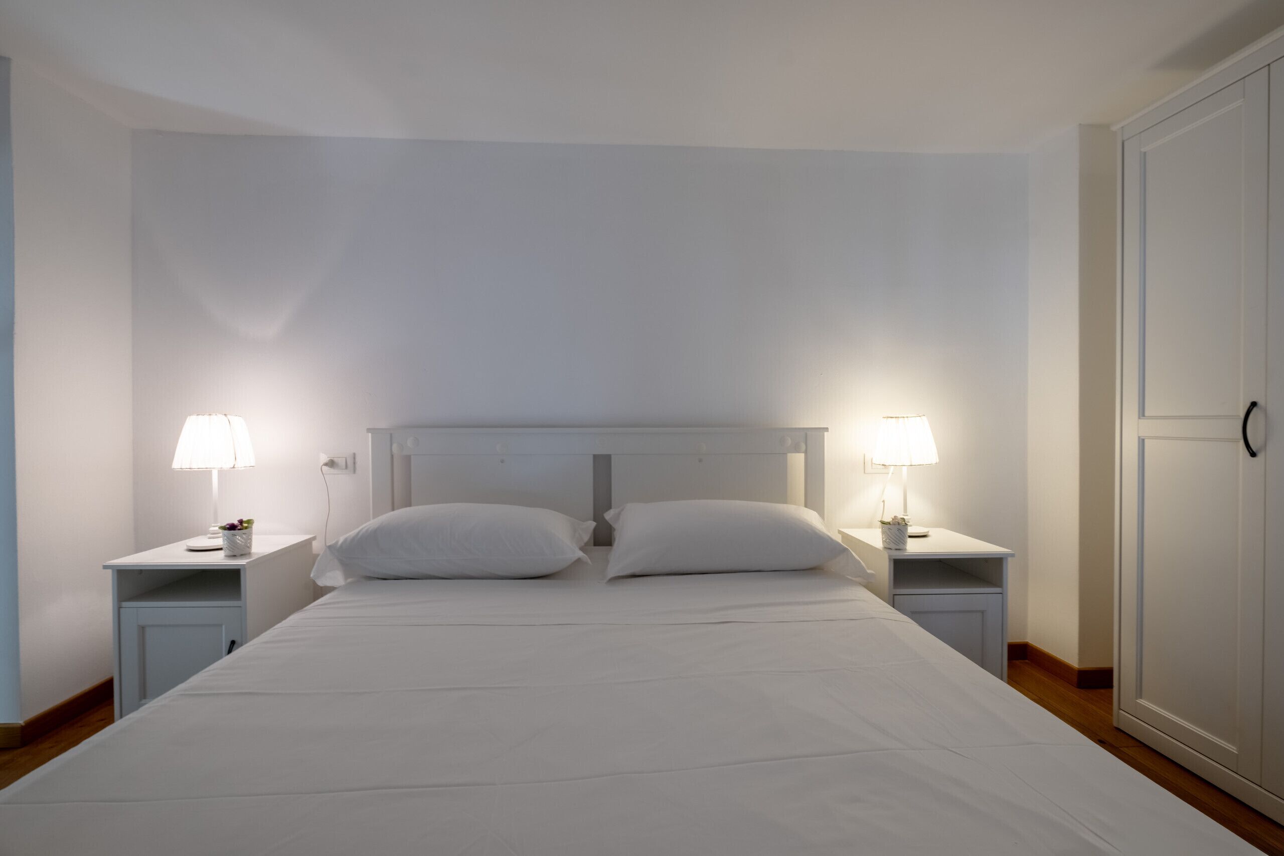 A bedroom with a single bed, two bedside tables, and two lamps.