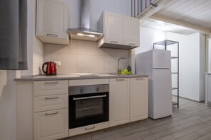 Eine moderne Küche mit weißen Schränken, einer Edelstahl-Dunstabzugshaube, einem Einbauofen und einem weißen Kühlschrank.