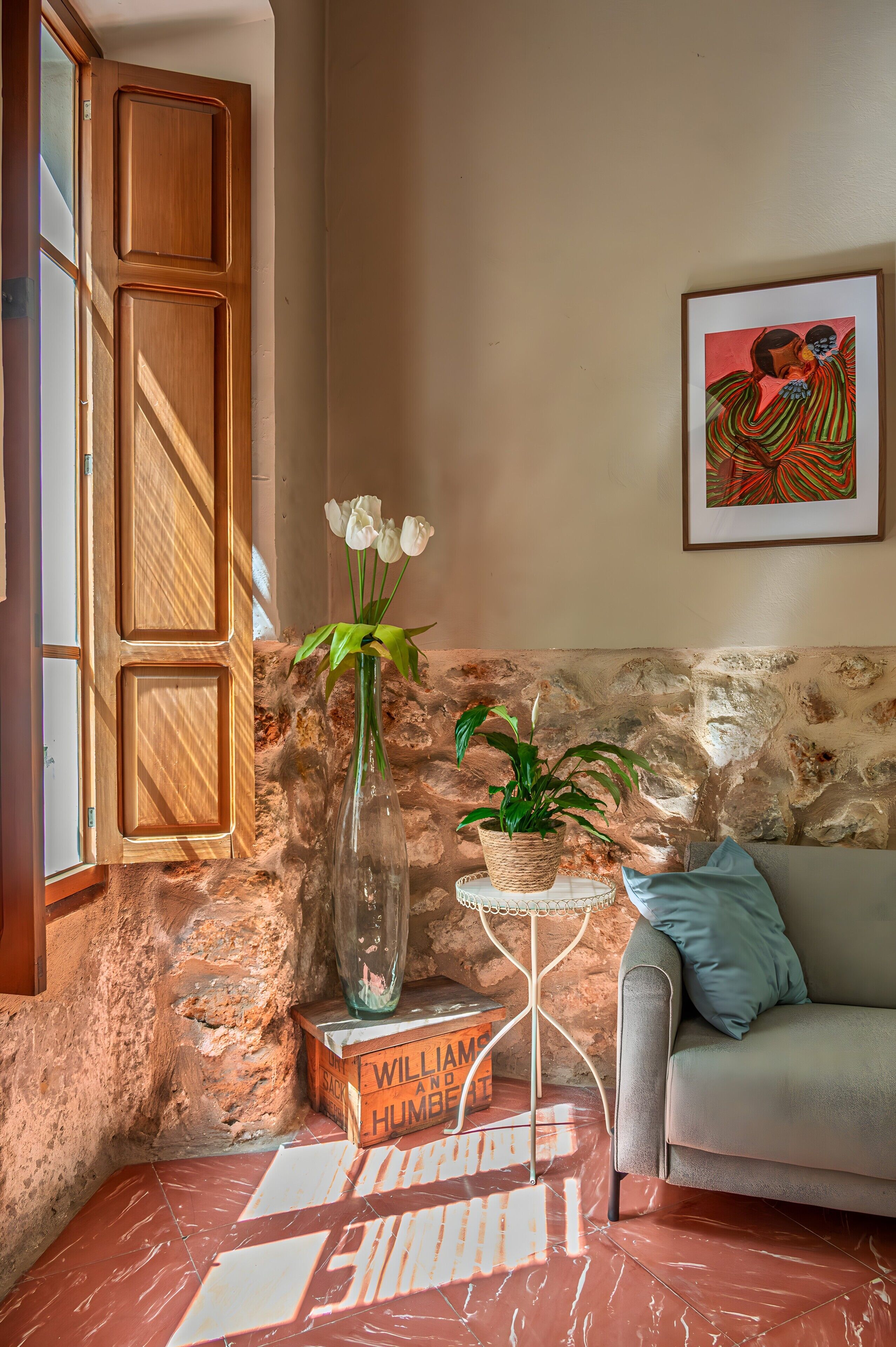 Et rum med en trædør, en vase med hvide blomster, en potteplante, et indrammet kunstværk og en sofa.