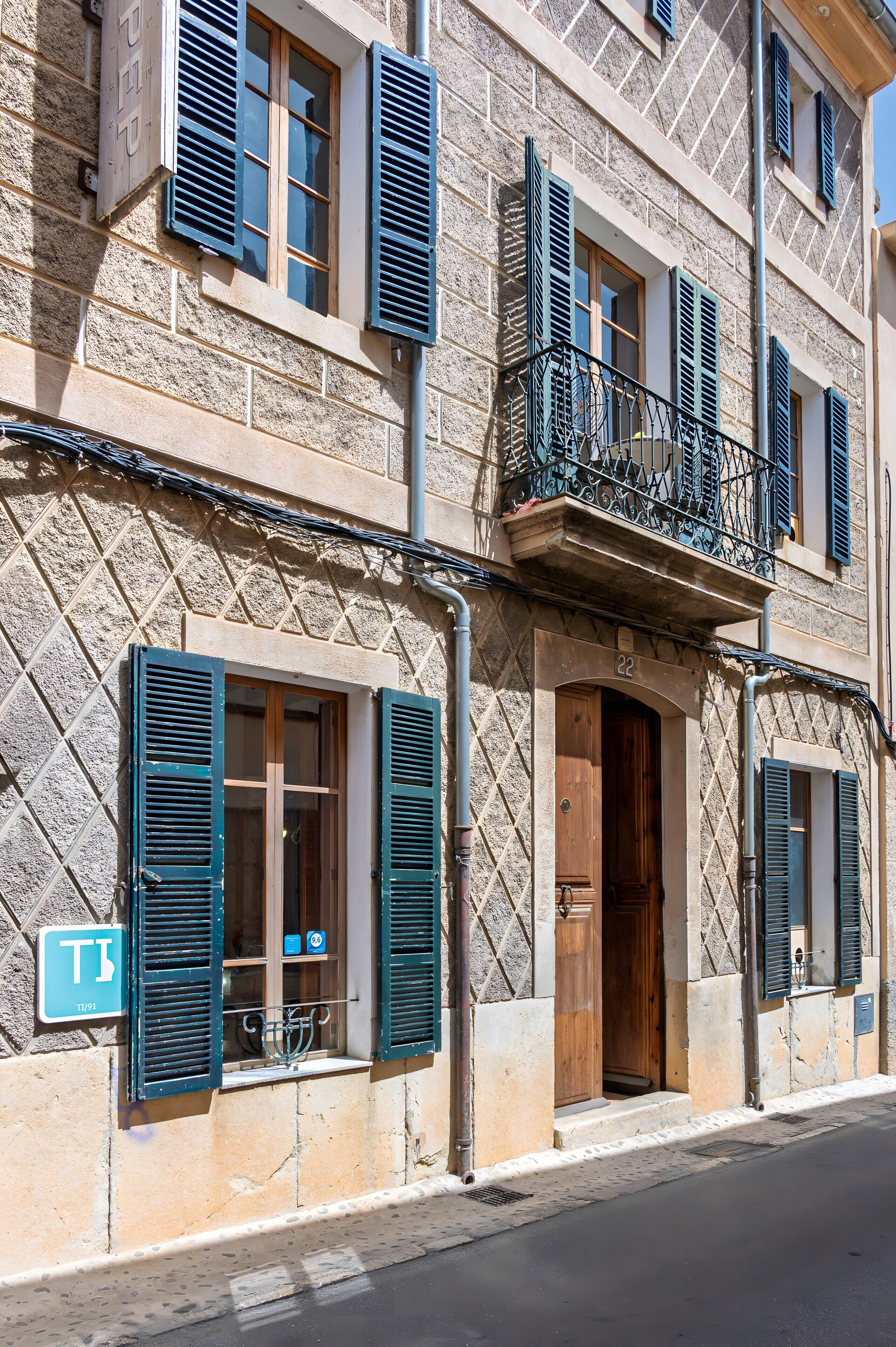 A building with multiple windows, some with shutters, a visible door, and a sign indicating a room number.