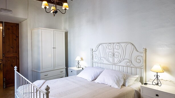 A bedroom with a bed, nightstands, a wardrobe, and a chandelier.