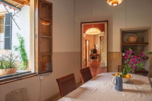 A dining area with a table set for two, chairs, a vase with flowers, and a window with shutters. - Maria Magdalena Room (Alaró)