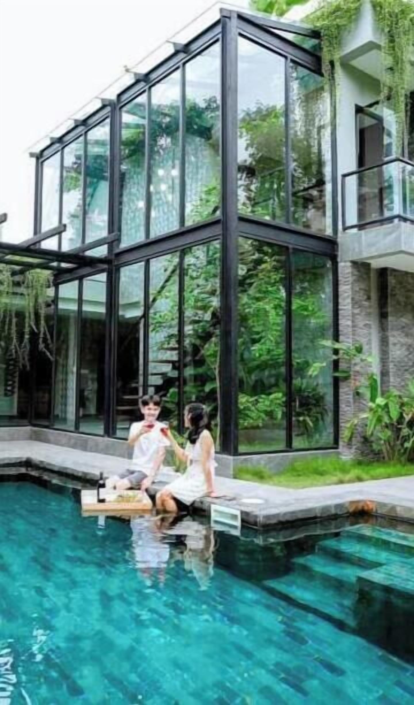 A modern house with a glass facade, a swimming pool, and a garden.