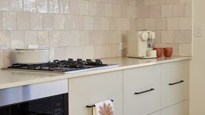 A kitchen with a gas stove, a coffee machine, and a pot on the counter.