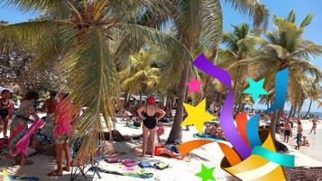 A beach with palm trees and people sunbathing.