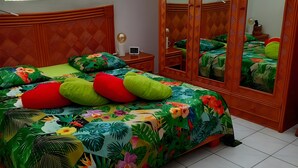 Un dormitorio con cama, armario, espejo y mesita de noche.