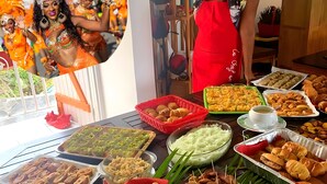 Una mesa de buffet con diversos alimentos y una persona con delantal rojo.