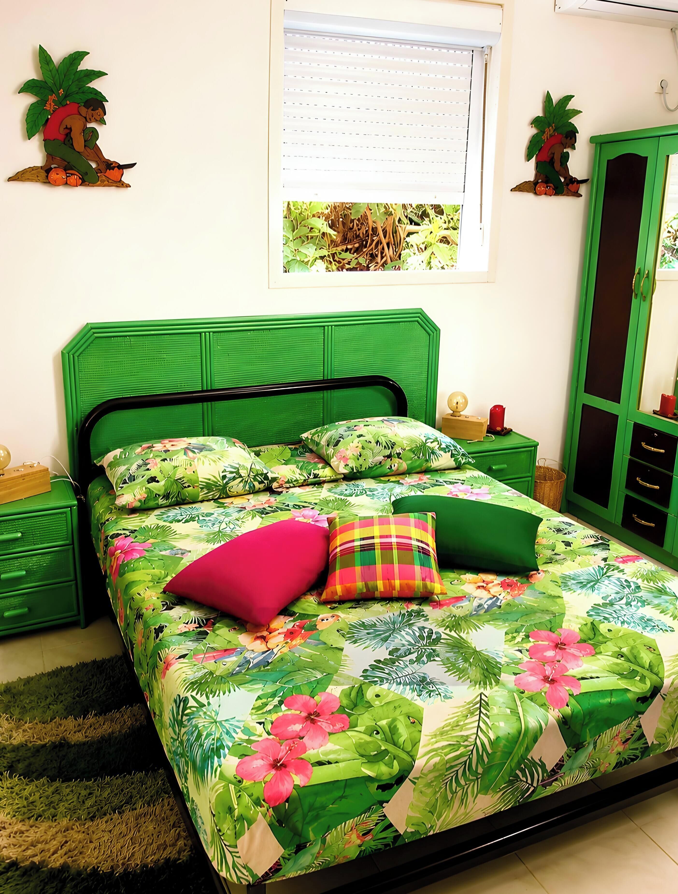 Un lit avec une couvre-lit à motifs floraux, une tête de lit verte et plusieurs oreillers.