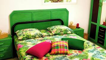 Un lit avec une couvre-lit à motifs floraux, une tête de lit verte et plusieurs oreillers.