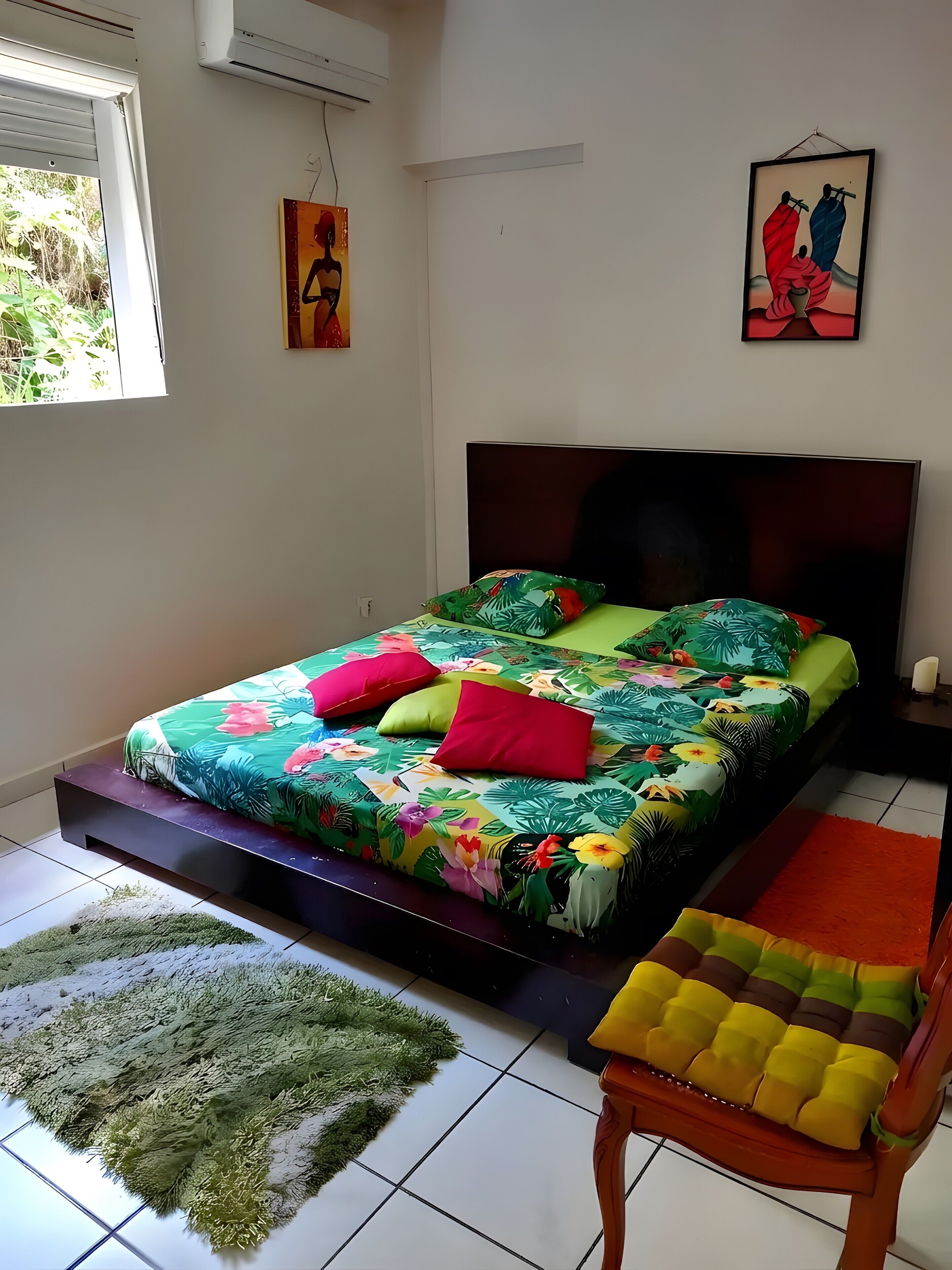 A bedroom with a bed, a chair, a rug, and artwork on the walls.