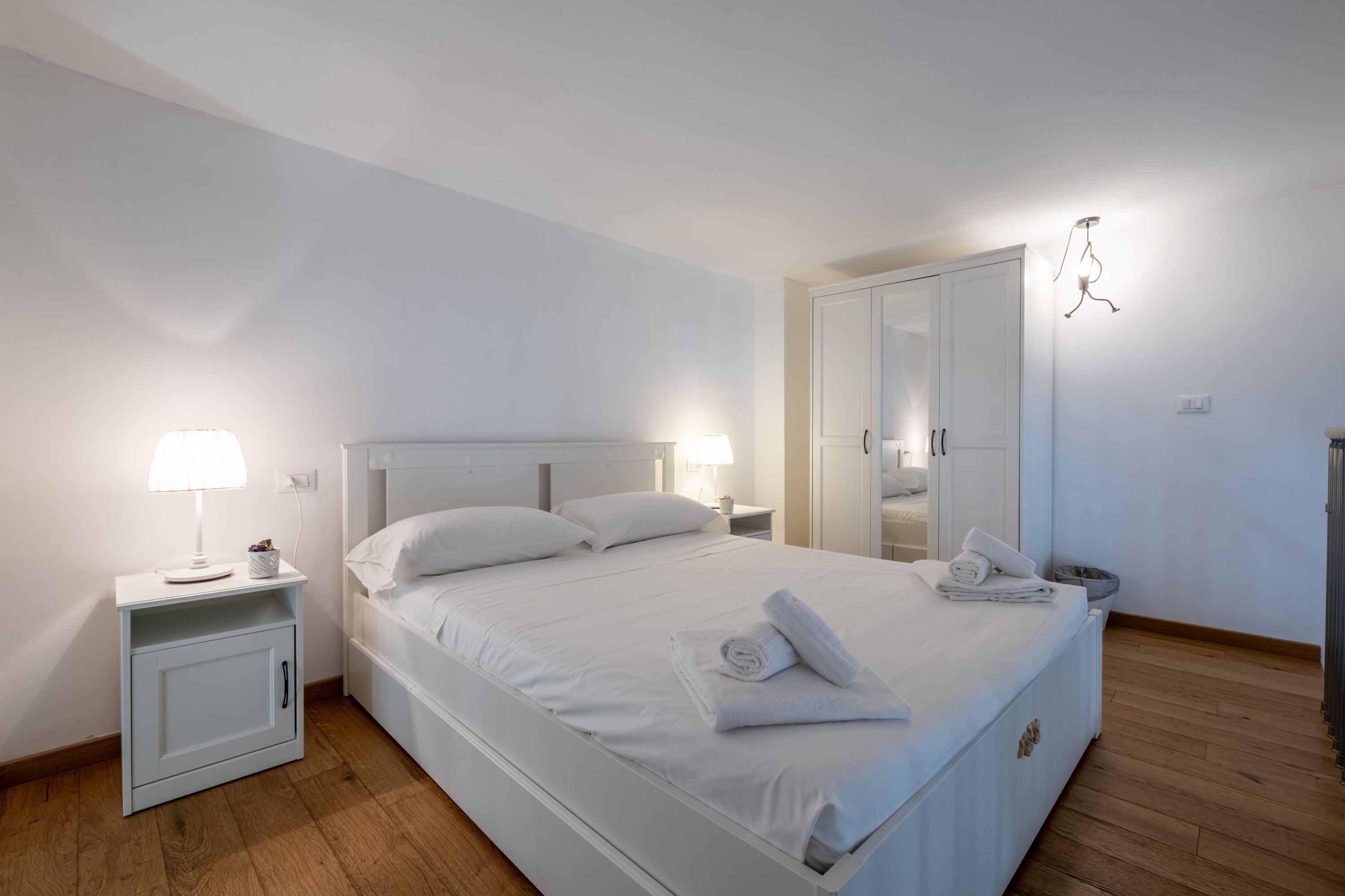 Ein Schlafzimmer mit einem Einzelbett, Nachttischen, einem Kleiderschrank und einer Hängeleuchte.