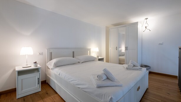 A bedroom with a single bed, bedside tables, a wardrobe, and a hanging light fixture. - Caduti di Via Fani by Wonderful Italy (Bologna)